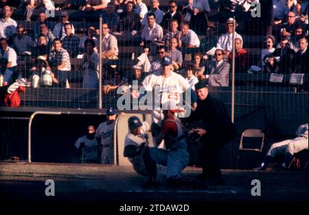LOS ANGELES, CA - 7 LUGLIO: Wally Moon #9 dei Los Angeles Dodgers scivola tranquillamente sotto il tag dal ricevitore Jerry Zimmerman #8 dei Cincinnati Reds come arbitro di casa Tom Gorman è lì per fare la chiamata mentre Frank Howard #25 dei Dodgers guarda durante la prima partita del double header il 7 luglio 1961 al Los Angeles Memorial Coliseum di Los Angeles, California. (Foto di Hy Peskin) *** didascalia locale *** Frank Howard;Wally Moon;Jerry Zimmerman;Tom Gorman Foto Stock