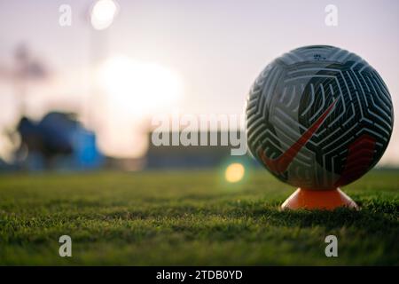 Una palla da calcio riposa sul campo prima di una partita mentre i giocatori eseguono il riscaldamento pre-partita Foto Stock