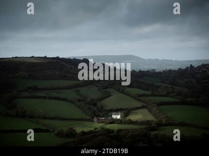 Una macchia di luce illumina un casale solitario in un paesaggio pastorale. Dorset, Regno Unito. Foto Stock