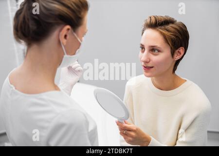 Una giovane donna consulta un'estetista sul suo viso. Foto Stock