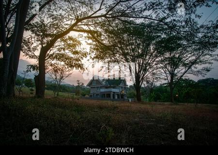 una casa sul fianco della montagna tra gli alberi e al crepuscolo Foto Stock