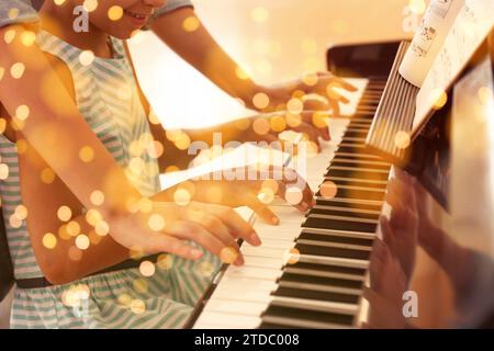 Musica di Natale e Capodanno. Una donna con una bambina che suona il piano in casa. Effetto bokeh Foto Stock