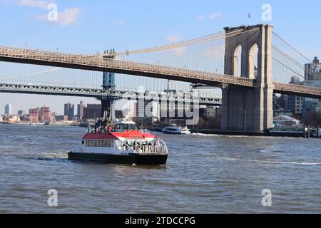 Taxi d'acqua sull'East River passando sotto i ponti di Manhattan e Brooklyn a New York Foto Stock