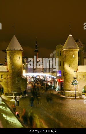 Torri di pietra della porta Viru con centinaia di acquirenti e folle festose che camminano (movimento sfocato) verso il mercato di Natale nella città vecchia di Tallinn, Estonia Foto Stock