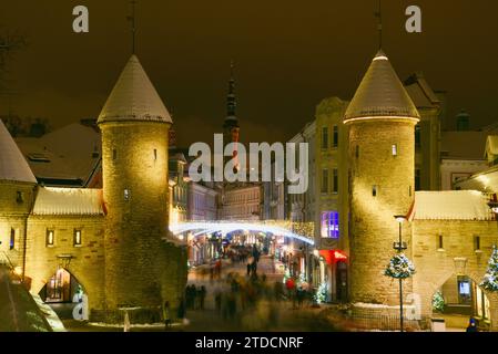 Torri di pietra della porta Viru con centinaia di acquirenti e folle festose che camminano (movimento sfocato) verso il mercato di Natale nella città vecchia di Tallinn, Estonia Foto Stock