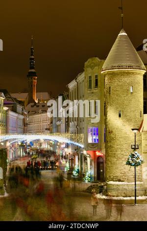 Torri di pietra della porta Viru con centinaia di acquirenti e folle festose che camminano (movimento sfocato) verso il mercato di Natale nella città vecchia di Tallinn, Estonia Foto Stock