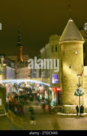 Torri di pietra della porta Viru con centinaia di acquirenti e folle festose che camminano (movimento sfocato) verso il mercato di Natale nella città vecchia di Tallinn, Estonia Foto Stock