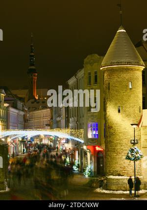 Torri di pietra della porta Viru con centinaia di acquirenti e folle festose che camminano (movimento sfocato) verso il mercato di Natale nella città vecchia di Tallinn, Estonia Foto Stock