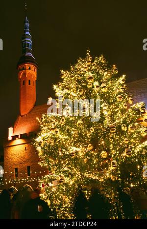 Mercatino di Natale nella piazza del Municipio festeggia con un enorme albero di Natale decorato con luci e bulbi di vetro dorato nella neve del centro storico di Tallinn, Estonia Foto Stock