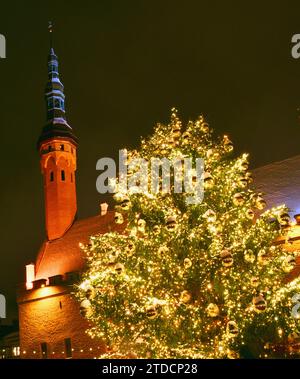 Mercatino di Natale nella piazza del Municipio festeggia con un enorme albero di Natale decorato con luci e bulbi di vetro dorato nella neve del centro storico di Tallinn, Estonia Foto Stock