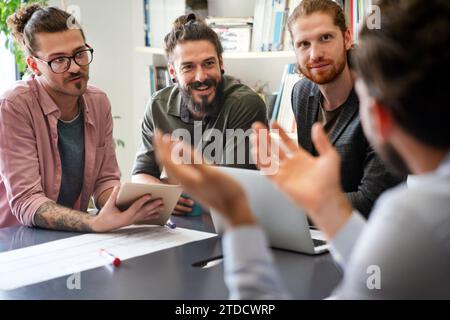 Un team di giovani sviluppatori di software multietnici parla e discute di un progetto di intelligenza artificiale. Startup aziendale Foto Stock