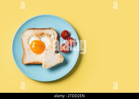 Colazione di San Valentino con uova con pomodori, pane a forma di cuore e pane tostato su sfondo giallo Foto Stock