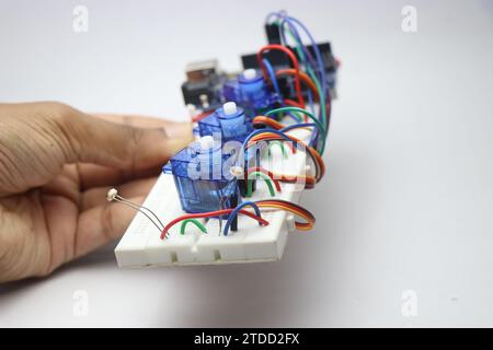 Breadboard con fili e microservomotori collegati a un chip elettronico Foto Stock