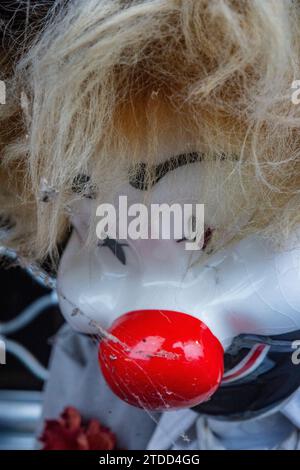 Primo piano di una bambola clown. Pelle bianca, capelli biondi, naso rosso. Spettrale, infestata, classica faccia da clown. Foto Stock