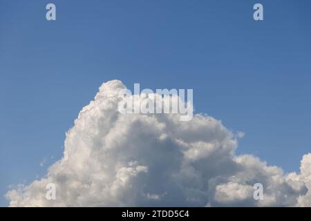 Un'unica e massiccia nuvola di cumulus, a forma di montagna, ha origine dalla parte inferiore della fotografia, la sua vetta svetta come una montagna Foto Stock