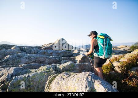 Vista laterale di una determinata escursionista che raggiunge la vetta della montagna. Foto Stock