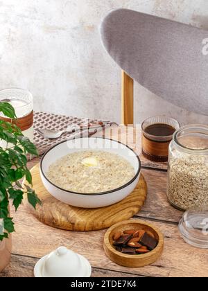 porridge di farinata d'avena in un recipiente con un pezzo di burro sul tavolo Foto Stock