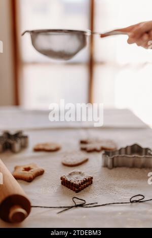 Cospargere di zucchero i biscotti e le taglierine di natale su un'accogliente tovaglia Foto Stock