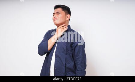 Giovane uomo asiatico che tocca la gola mostrando in espressione dolore su sfondo bianco. foto studio Foto Stock