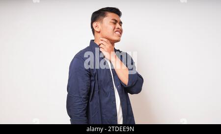 Giovane uomo asiatico che tocca la gola mostrando in espressione dolore su sfondo bianco. foto studio Foto Stock