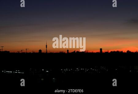 München, Deutschland 17. Dicembre 2023: Hier der Blick von der Esplanade, Allianz Arena auf die Skyline von München bei Dämmerung, Abend, Sonnenuntergang, in der Mitte kann man den Olympiaturm, Fernsehturm erkennen, Färbung, Farbenspiel, Monaco di Baviera, Häuser Foto Stock