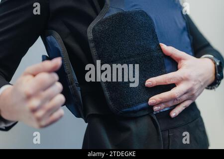 Colonia, Germania. 18 dicembre 2023. La Bailiff Georgia Papapostolou indossa il suo nuovo giubbotto protettivo durante un evento stampa. Il primo dei 750 giubbotti protettivi per ufficiali giudiziari in tutto il paese è stato consegnato al tribunale distrettuale di Colonia. Crediti: Marius Becker/dpa/Alamy Live News Foto Stock