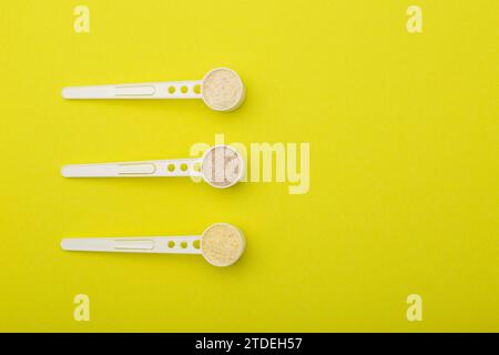 Un set di cucchiai con diversi tipi di grano saraceno, riso e porridge di grano su sfondo giallo. Cereali senza latticini con vitamine e minerali per bambini Foto Stock