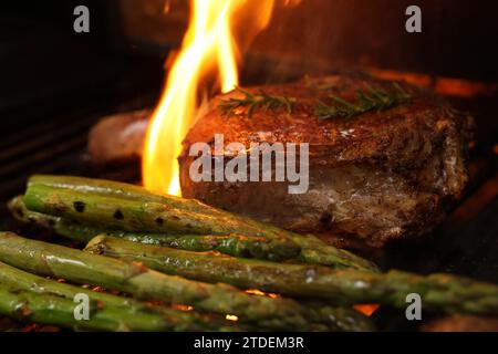 Cucinare una bistecca di costata su un grill, un grill o un barbecue. Una costoletta con osso che sfrigolerà un barbecue con fiamma o fiamme. Concetto di carne di manzo Foto Stock