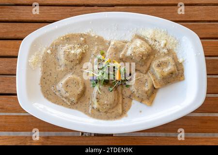 Una vista a volo d'uccello su un piatto di ravioli di funghi freschi su un tavolo di legno Foto Stock