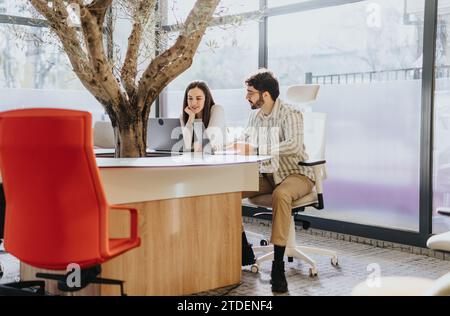 Un team di successo multi-generazionale collabora alla strategia di espansione aziendale lavorando in un ufficio moderno e soleggiato. Foto Stock