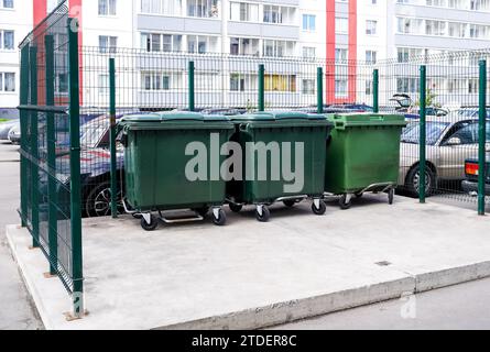 Contenitori di plastica verde nel cortile di un condominio in estate Foto Stock