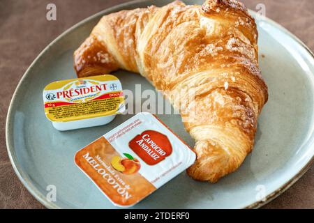 immagine ravvicinata di un croissant appena sfornato servito con burro e marmellata sul piatto Foto Stock