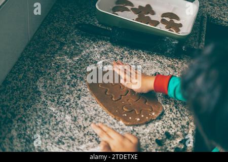 Madre e figlio si rafforzano mentre condividono risate e amore mentre preparano il pan di zenzero di Natale Foto Stock