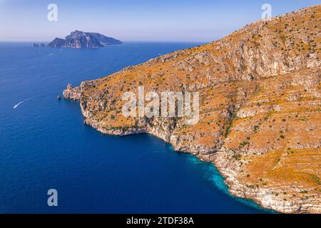 Vista aerea di una costa rocciosa di fronte alle acque blu del Mar Tirreno con l'isola di Capri sullo sfondo, la Costiera Amalfitana Foto Stock