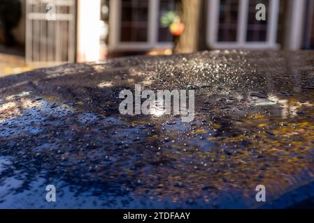 gocce d'acqua sul tetto nero dell'auto dopo aver smesso di piovere, messa a fuoco selettiva Foto Stock