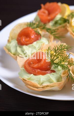 Avocado montato con crema di formaggio soffice nella mousse più delicata, una fetta di salmone e limone. Servita in cesti croccanti con pasta phyllo cotta al forno Foto Stock