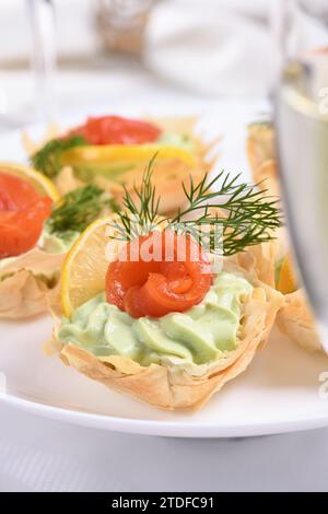 Avocado montato con crema di formaggio soffice nella mousse più delicata, una fetta di salmone e limone. Servita in cesti croccanti con pasta phyllo cotta al forno Foto Stock