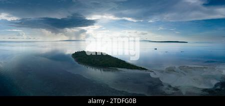 L'alba illumina la remota isola di Koon vicino a Seram, Indonesia. Le barriere coralline di quest'isola, e i mari circostanti, supportano un'elevata biodiversità marina. Foto Stock