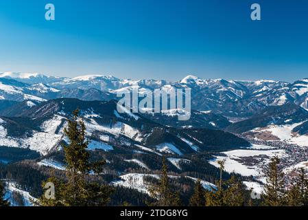 Liptovska Luzna villaggio con colline di Velka Fatra e Martinske hole in Mala Fatra montagne sullo sfondo in Slovacchia durante la giornata invernale con clea Foto Stock