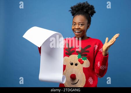 Giovane donna carina che legge una lettera di natale e si sente eccitata Foto Stock