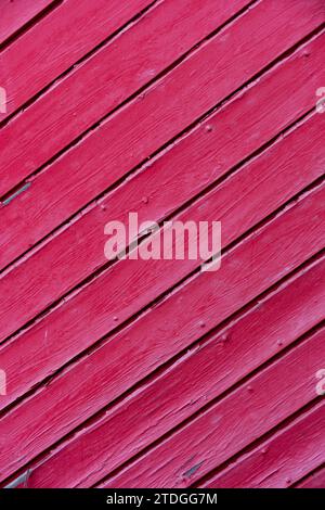 Primo piano, sezione di dettaglio astratta di pannelli di recinzione in legno rosa caldo con superficie verniciata e resistente agli agenti atmosferici e montata in diagonale. Foto Stock