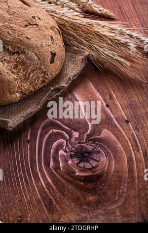 Pane e orecchie di grano su una vecchia tavola di legno Foto Stock
