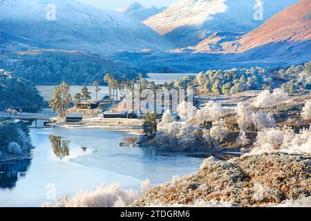 Glen Affric Cannich Scozia mattina presto soleggiata d'inverno colline innevate e una gelata bianca sopra il lago di betulla e pini e le case della tenuta Foto Stock