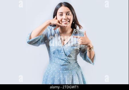 La giovane donna che gesto MI CHIAMA in linguaggio dei segni isolato. Gesti manuali di persone con problemi uditivi Foto Stock