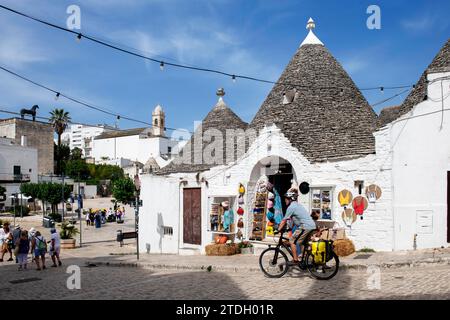 Ciclista tra trulli ad Alberobello, Valle d'Itria, Puglia, Italia Foto Stock