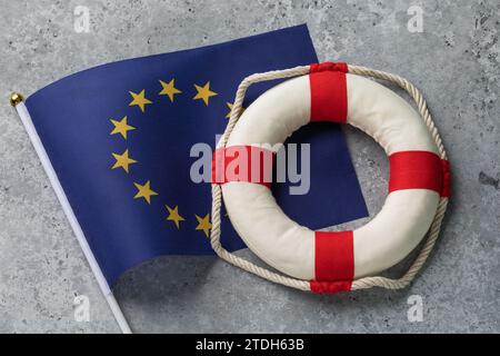 Bandiera e salvagente dell'Unione europea su un contesto astratto e concreto, concetto sul tema dell'assistenza dell'Unione europea Foto Stock