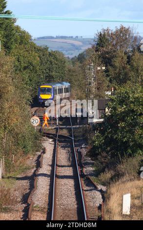 Il Network Rail Signaler chiuse i cancelli manuali dei passaggi a livello a Poppleton, nello Yorkshire, come parte un treno Northern Rail classe 170 TurboStar. Foto Stock