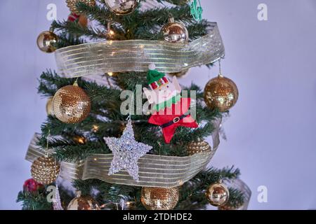 Decorazioni dell'albero di Natale, palline luccicanti dorate, una stella luccicante e un elfo appeso su un albero di natale su sfondo bianco. Spazio orizzontale e copia Foto Stock