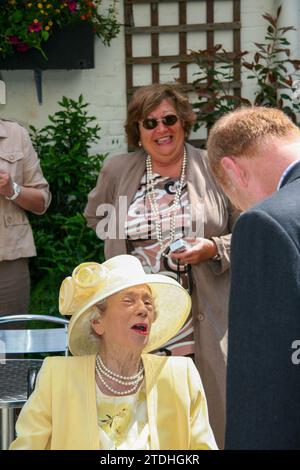 Una signora anziana di giallo limone con un cappello grande apre al nuovo bar/ristorante/sala funzioni sul retro del Crown Hotel Framlingham nel Suffolk Foto Stock