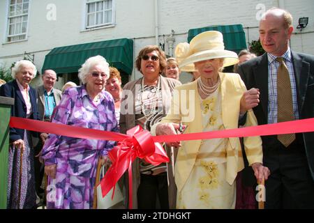 Una signora anziana di giallo limone con un cappello grande apre al nuovo bar/ristorante/sala funzioni sul retro del Crown Hotel Framlingham nel Suffolk Foto Stock